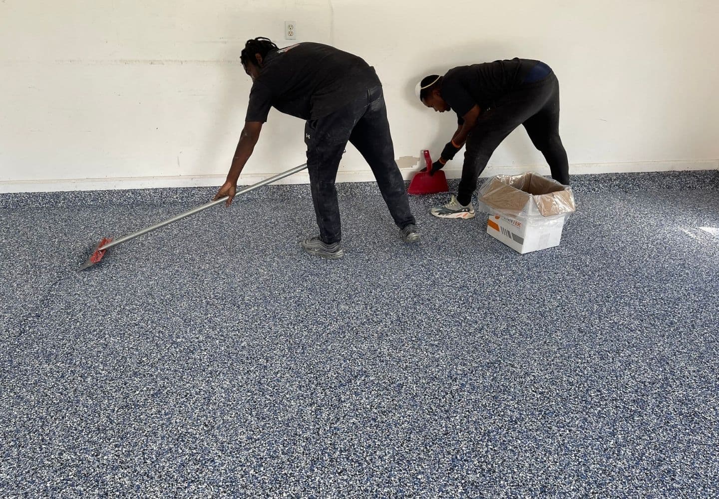 Professional installers applying a UV-stable flake polyaspartic coating to a Houston garage floor.